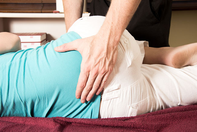 chiropractor assisting patient in stretching their lower back